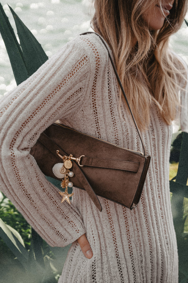 Zbliżenie na brelok Mare trzymany w dłoni na ciepłym brązowym tle