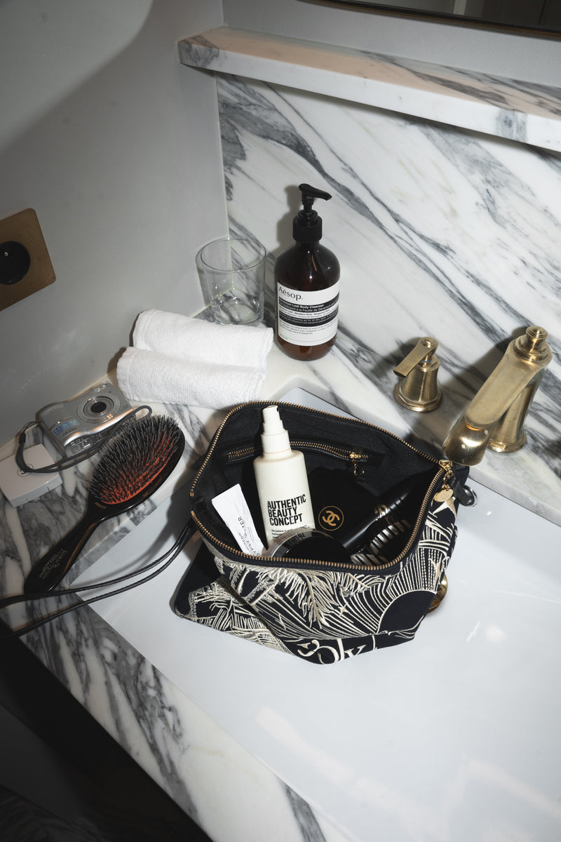 Kosmetyczka Vesper na marmurowym blacie z luksusowymi kosmetykami — łazienkowy flat lay