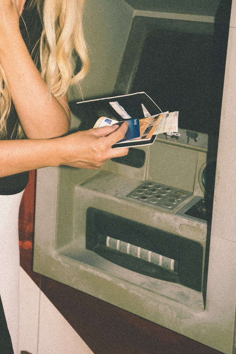 Dłoń z etui na paszport Caiman przy terminalu płatniczym — podróż w stylu